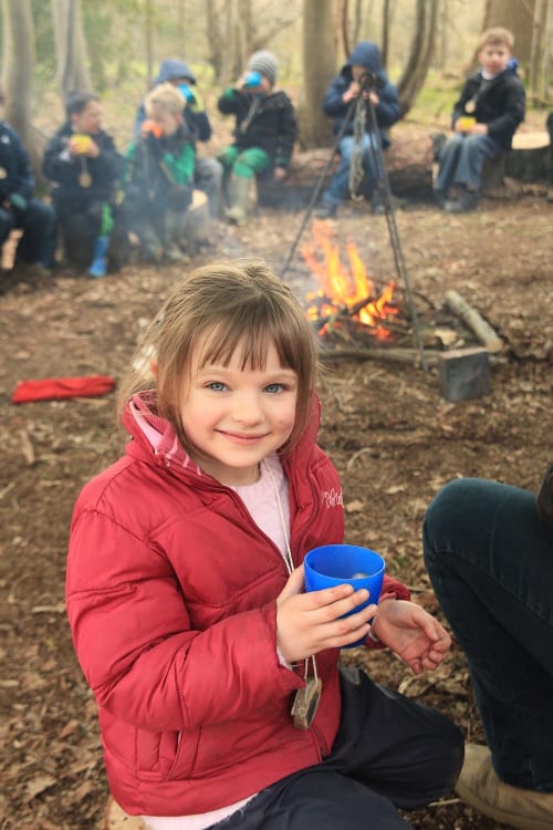 An image of a girl in front of the fire in the woods